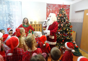 Mikołaj trzyma w ręku Mikrofon i mówi do dzieci.