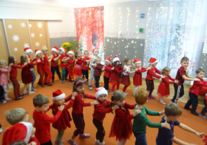 Dzieci ustawionę są jedno za drugim i tańczą wspólnie.