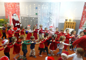 Inna grupa dzieci wspólnie tańczy trzymając się za ramiona.