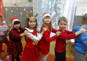 Inna grupa dzieci stoi jedno za drugim i trzyma się za ramiona.