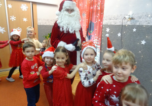 Kolejna grupa dzieci stoi jedno za drugim i trzyma się za ramiona.