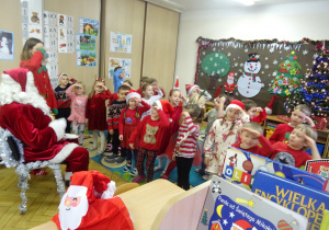 Dzieci stoją przed Mikołajem i unoszą ręce do czoła.