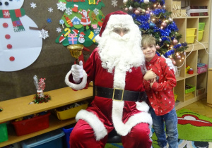 Chłopiec stoi obok Mikołaja.