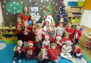 Grupa dzieci siedzi obok siebie i pozuje do zdjęcia.