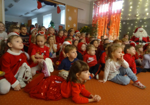 Inna grupa dzieci i Mikołaj siedzą na dywanie.