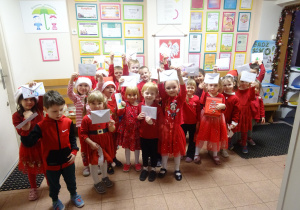 Grupa dzieci stoi wspólnie i trzyma w górze białe koperty.