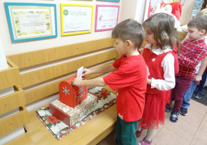 Inna grupa dzieci wrzuca listy do skrzynki świątecznej.