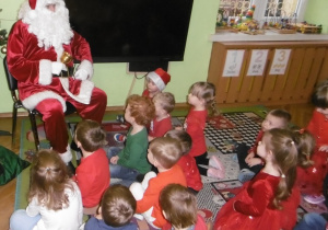 Mikołaj i dzieci siedzą wspólnie.