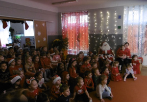 Grupa dzieci siedzi na dywanie.