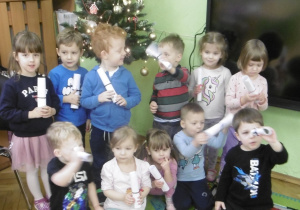 Grupa dzieci stoi razem i trzyma w rękach listy do Mikołaja.