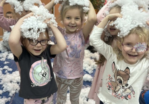 Dzieci trzymają sztuczny puch na głowie.