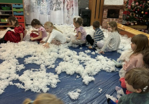 Zabawy dzieci w puchu na dywanie.