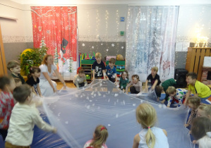 Dzieci podnoszą do góry i na dół białą chustę.