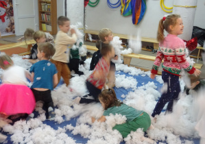 Dzieci bawią się w białym puchu.