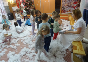 Zabawy dzieci na dywanie w otoczeniu białego puchu.