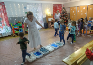 Osoba prowadząca warsztaty stoi przed ścieżką ułożoną z różnych materiałów.