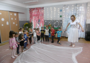 Grupa dzieci stoi przy białej chuście.