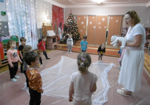 Dzieci stoją przy białej chuście.