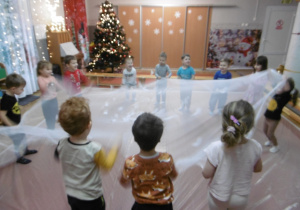 Grupa dzieci trzyma białą chustę.