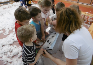 Dzieci stoją przed osobą prowadzącą warsztaty.