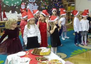 Dzieci stoją przy świątecznym stole.