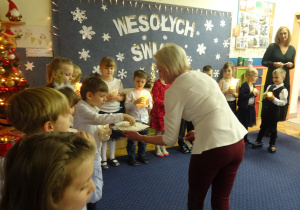 Rozdanie dzieciom opłatków przez nauczyciela.
