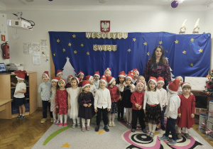 Grupa dzieci stoi razem z nauczycielką.