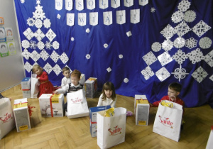 Grupa dzieci siedzi przy dekoracji.