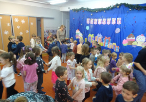 Dzieci trzymają się za ręce i razem tańczą.