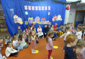 Dzieci podczas wspólnej zabway stoja na żótych kołach.