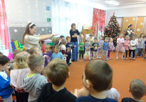 Dzieci stoją w kole i wykonują ruchy pokazane przez nauczycieli.