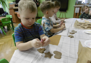 Chłopczyk dekoruje ciastko.