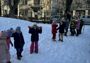 Dzieci stoją i machają rękami.