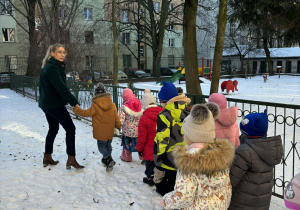Dzieci z nauczycielką podczas wspólnych zabaw zimowych.