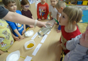 Dziewczynka wącha wodę w butelce.