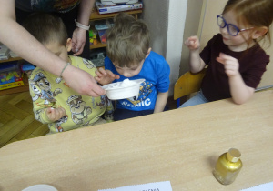 Dzieci siedzą przy stole i przyglądają się mące ziemniaczanej.