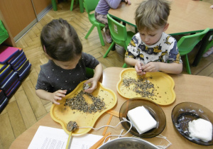 Dwoje dzieci wykonuje kulkę z nasion.