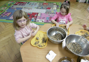 Dwie dziewczynki łączą nasiona w kulkę.