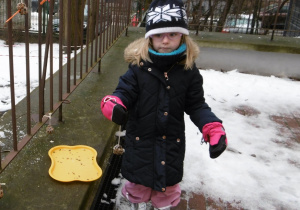 Dziewczynka stoi i trzyma w ręku kulkę z nasion.