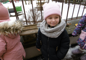 Dziewczynka stoi przy ogrodzeniu tarasu.