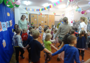 Dzieci tańczą trzymając się za ręce.