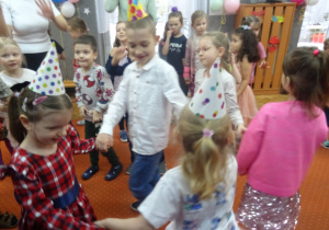 Dzieci trzymają się za ręce i wspólnie bawią się.