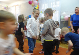 Chłopcy stoją obok siebie i trzymają ręcę na udach.