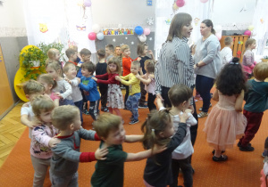 Dzieci idą za sobą trzymając ręce na ramionych.