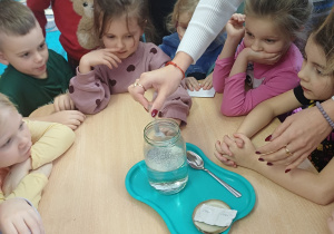 Nauczycielka pokazuje słoik z wodą.