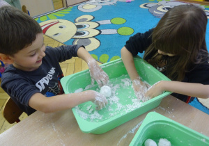 Dwoje dzieci lepi białe kulki.