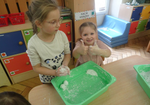 Dwoje innych dzieci lepi białe kulki.