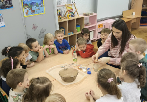 Nauczycielka i dzieci siedzą przy stoliku.