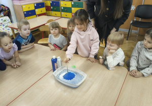 Dziewczynka włada pędzelk do niebieskiej wody.