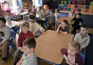 Grupa dzieci siedzi w sali przy stoliku.